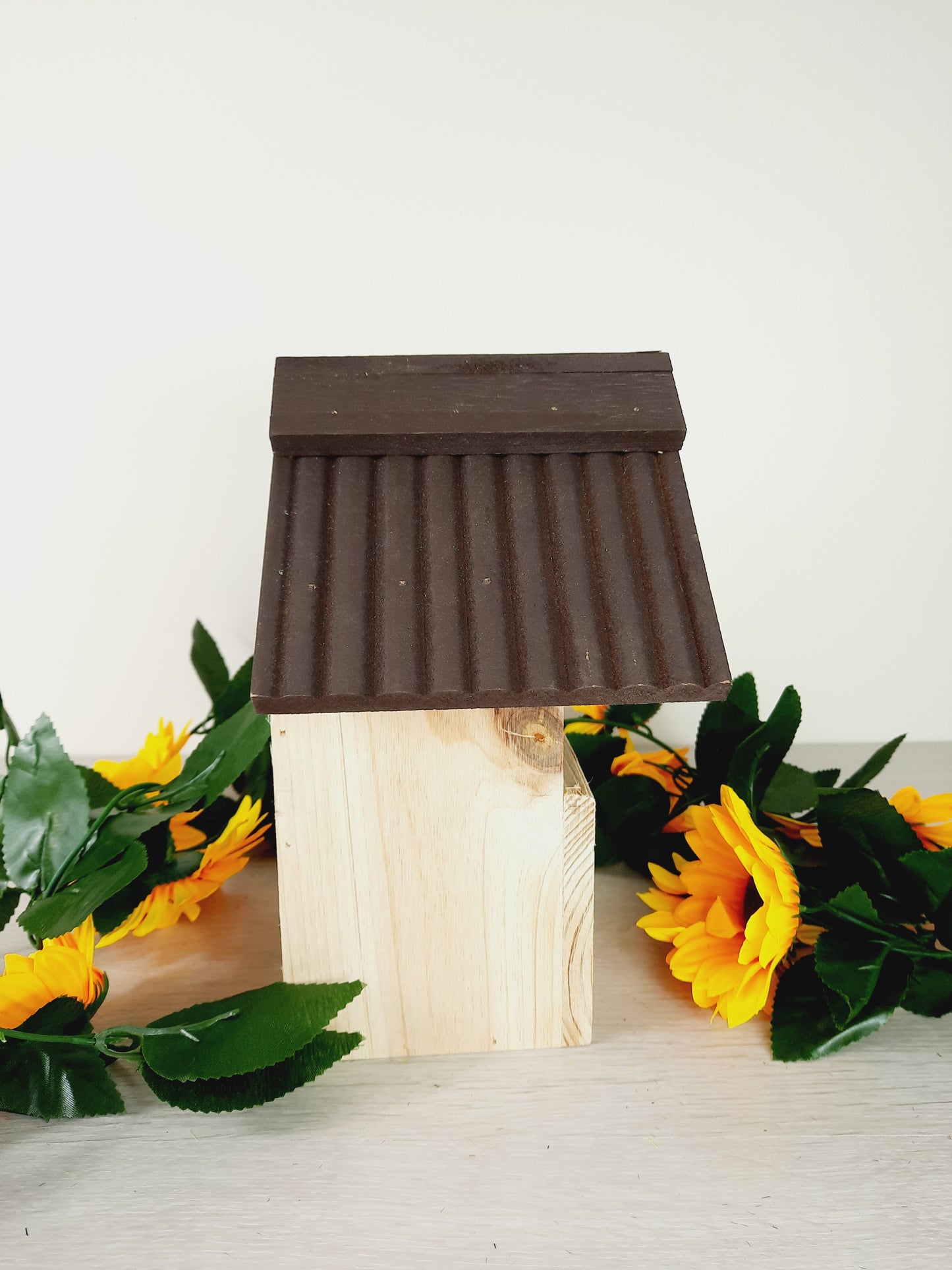Side profile of the bird nesting box with faux sunflowers as props.