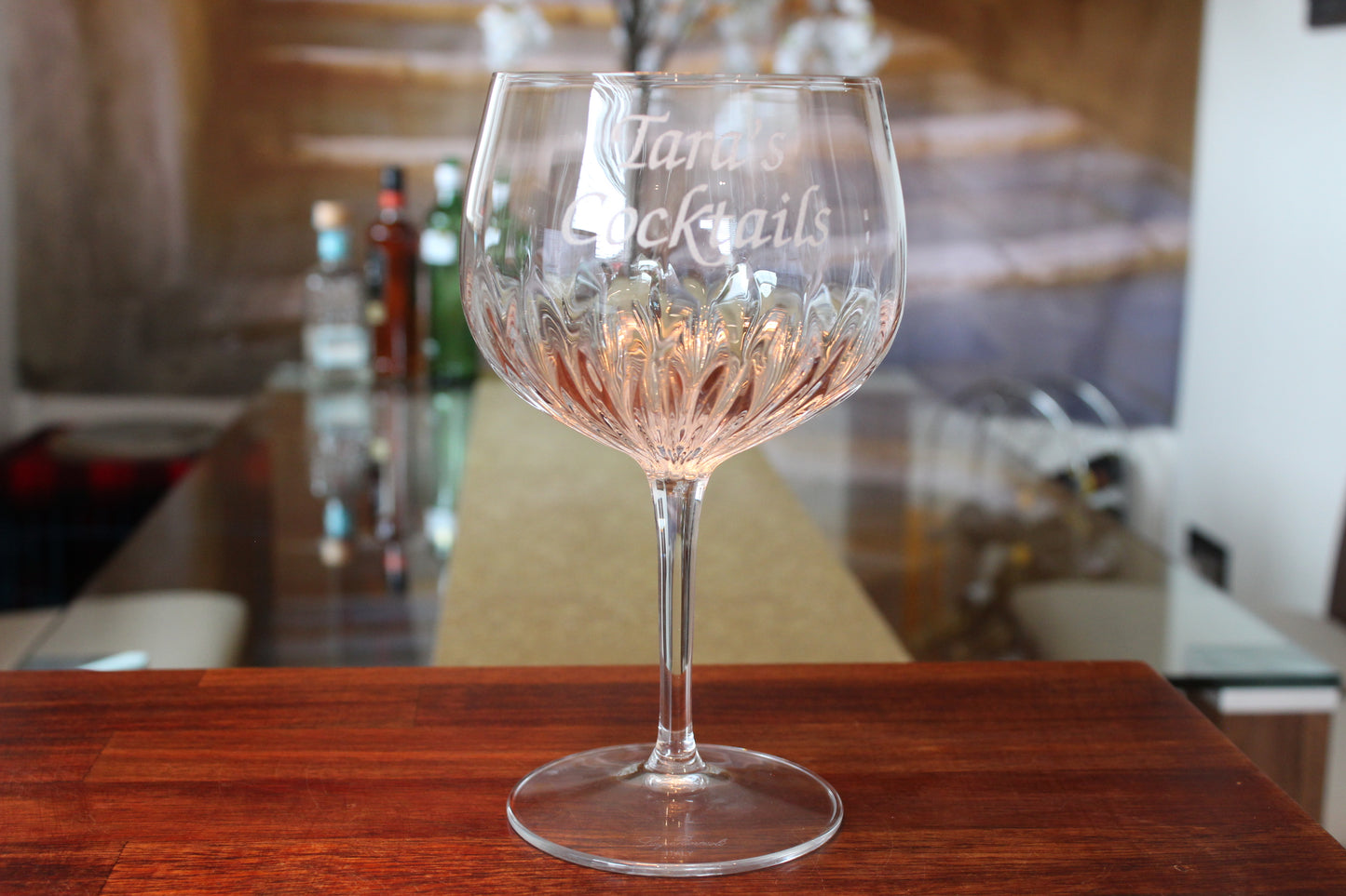 Personalised crystal cut gin glass that says "Tara's Cocktails" and it was placed on the table.