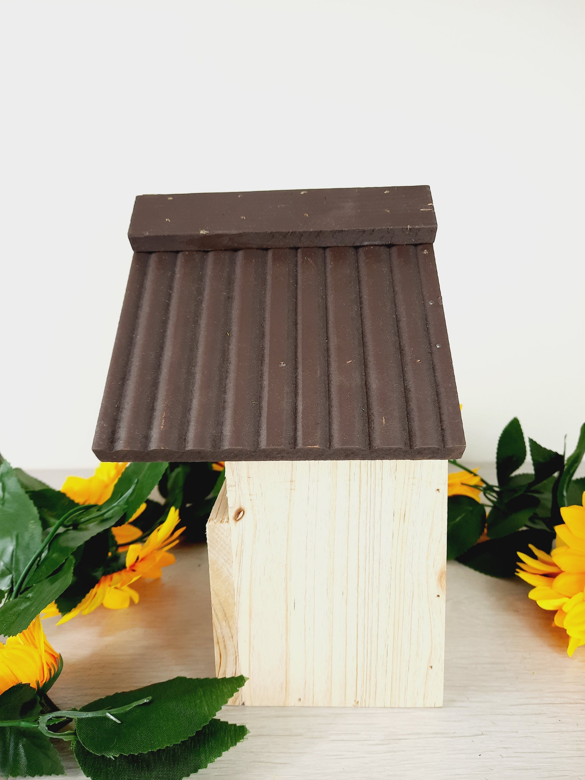 Side profile of the bird nesting box with faux sunflowers as props.