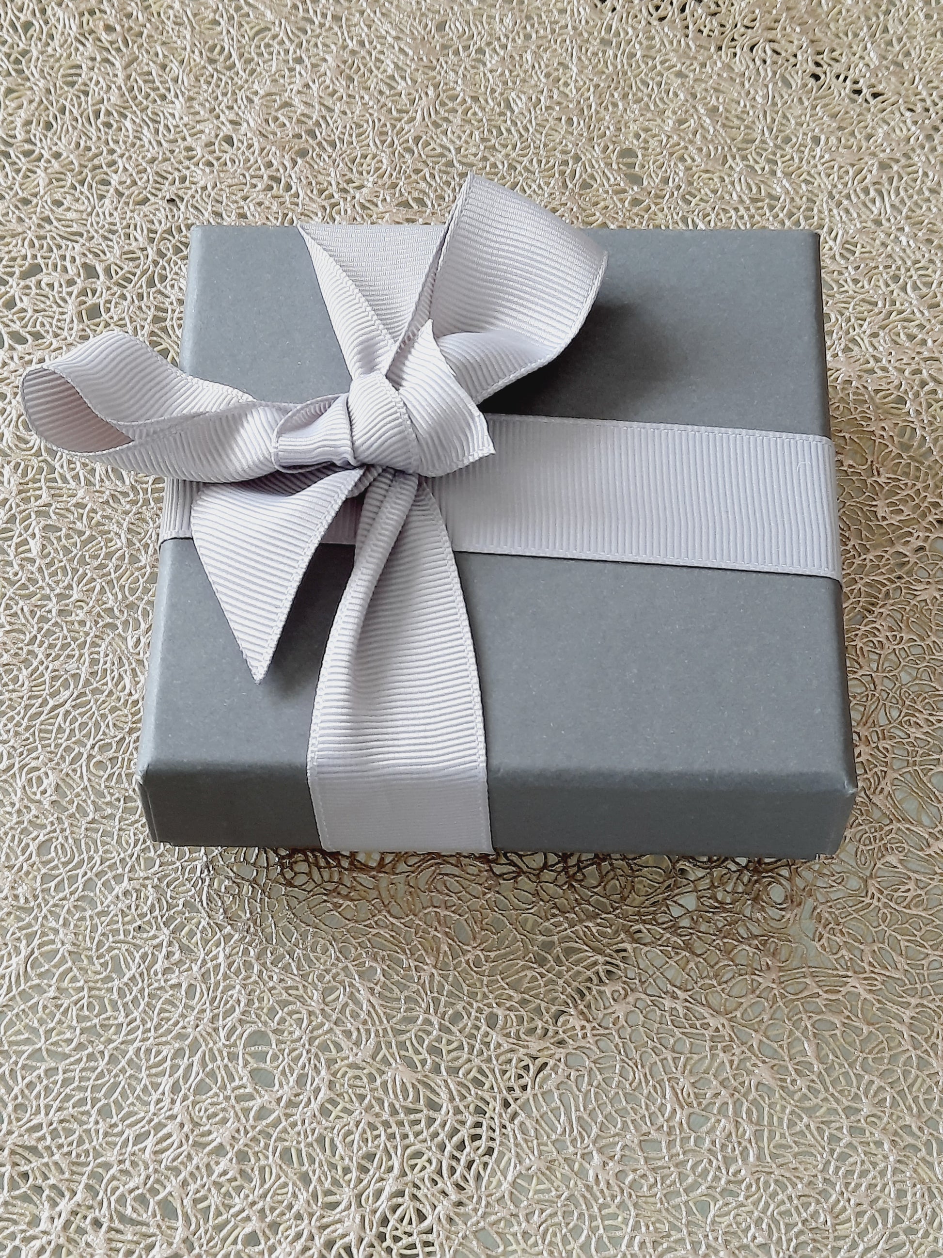 A small gray gift box with silver ribbon.