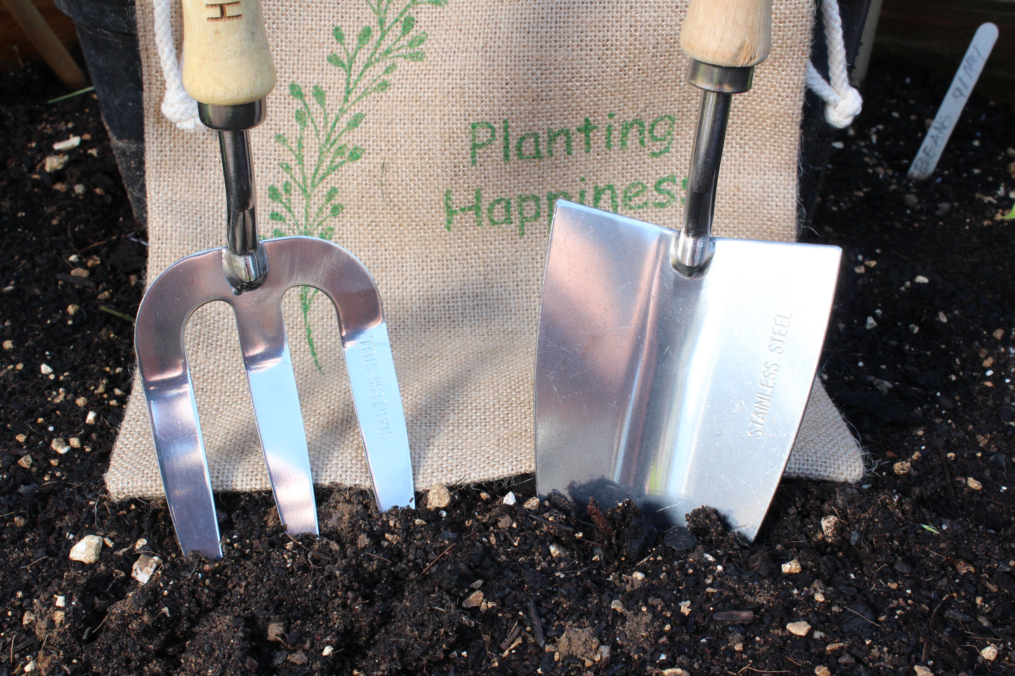 close up image of steel trowel and fork in jute gift bag