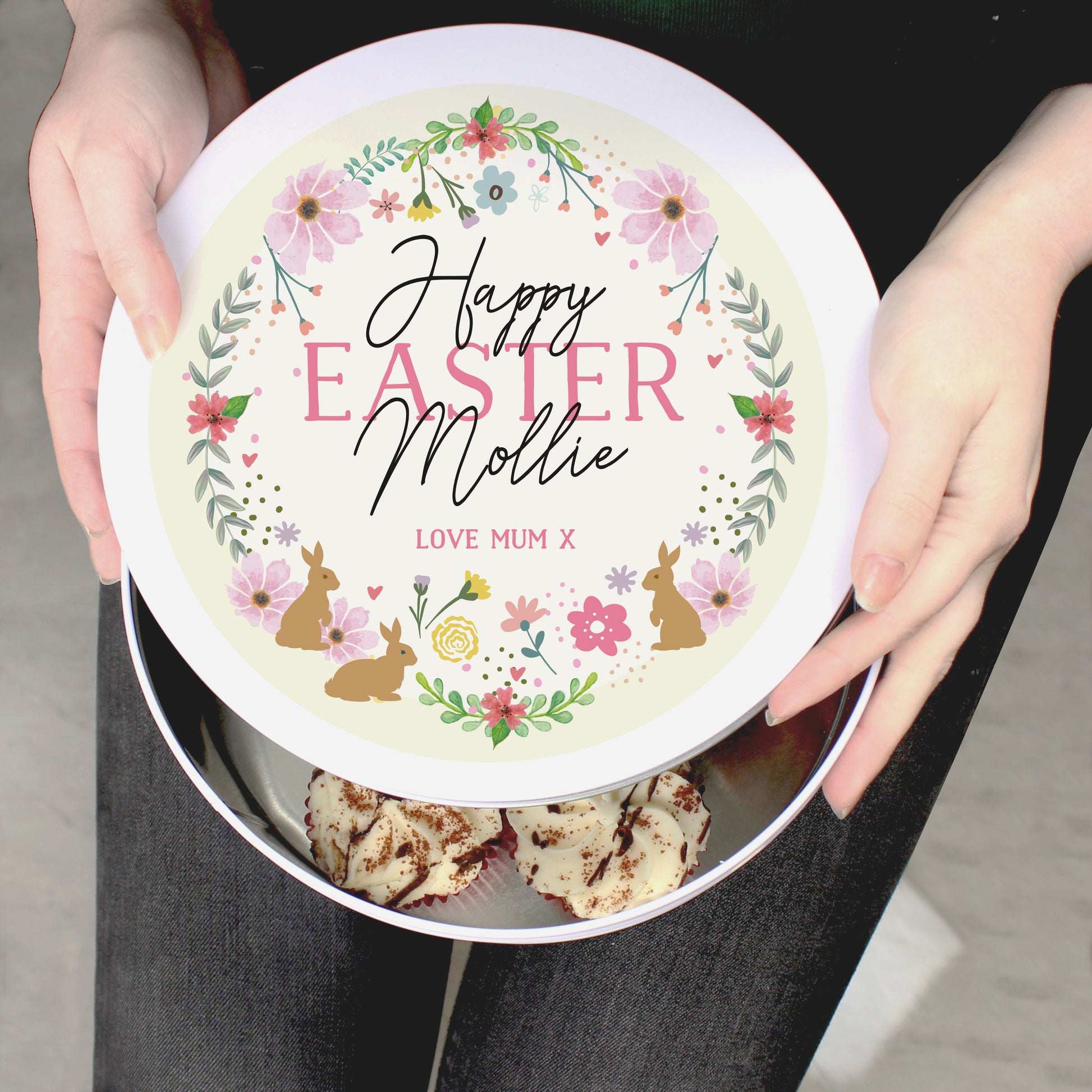 A woman is holding a Personalised Floral Cake Tin that says "Happy EASTER Mollie LOVE MUM X"
