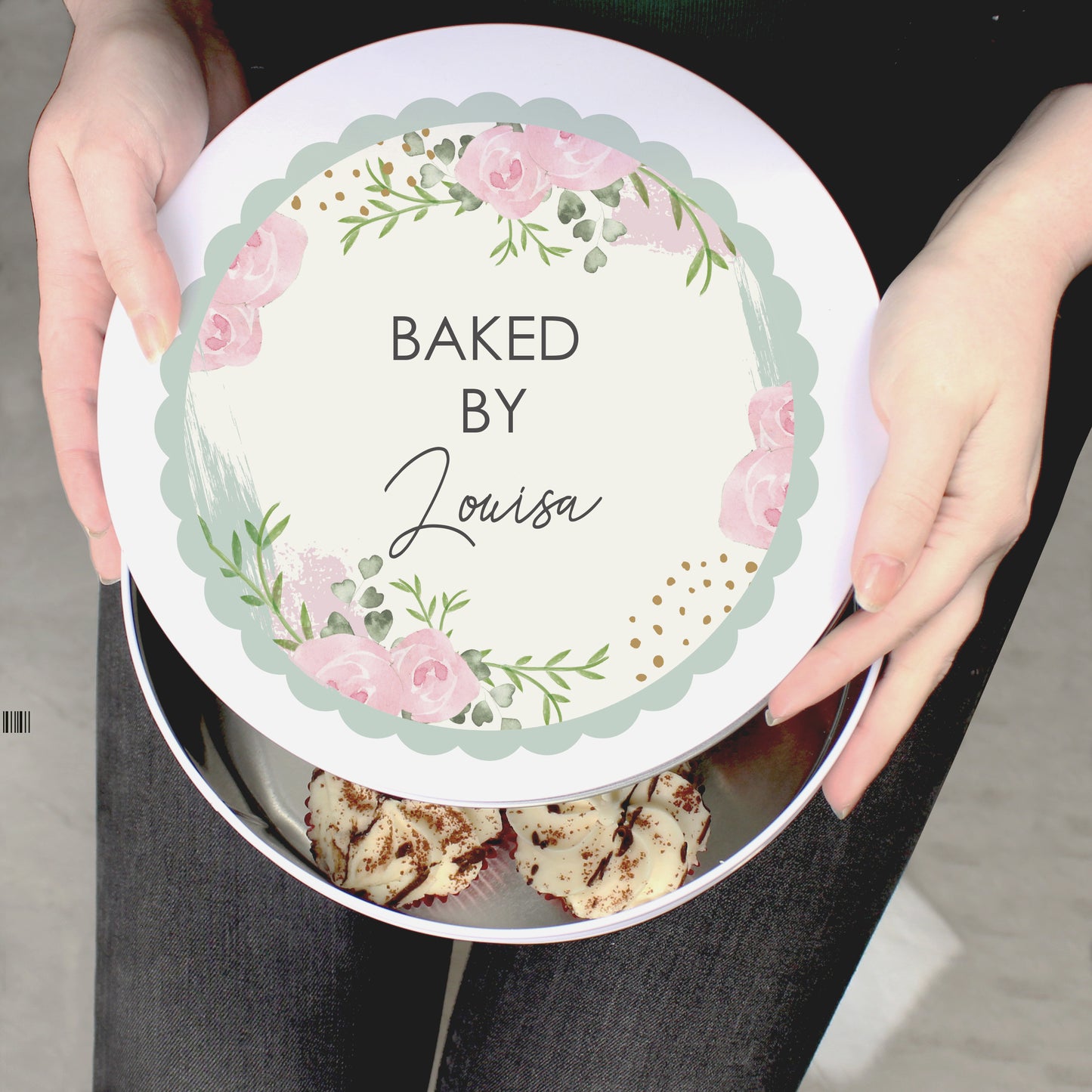 A woman is holding a Personalised Floral Cake Tin that says "BAKED BY Louisa"